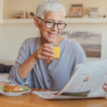 woman drinking juice reading newspaper at breakfast