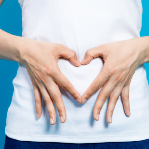 Woman holding a heart sign with hands at her stomach
